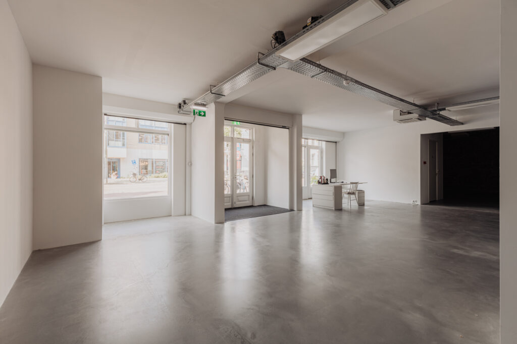 Licht en modern kantoorinterieur aan de Plantage Middenlaan met grote ramen en een minimalistisch bureau.